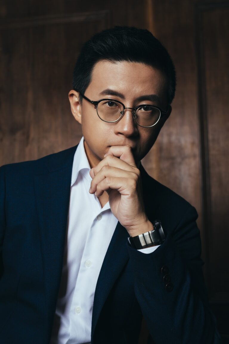 呱吉穿深色西裝、手托下巴的正式肖像